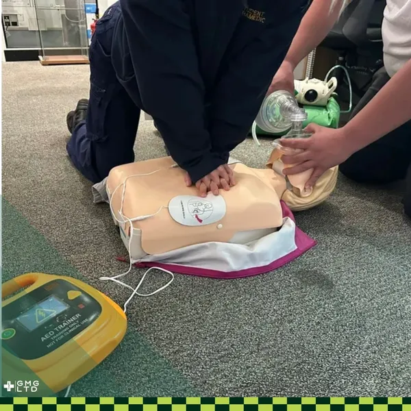 A trainee practising CPR on a manikin with an AED trainer